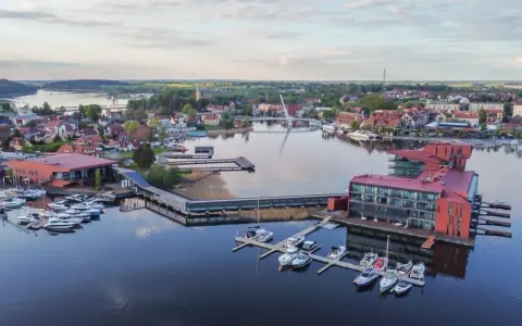 Mazury słyną z malowniczych jezior i portów pełnych jachtów. Widok na miasteczko z nowoczesnymi budynkami i wodnymi atrakcjami.
