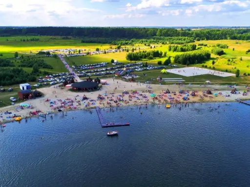 Tłumy ludzi wypoczywają na plaży i w wodzie. Idealne miejsce, gdzie nad wodę Dolny Śląsk zaprasza na wakacje.