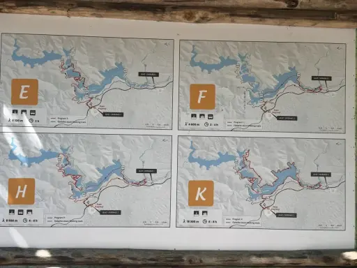 Plany czterech tras pieszych: E, F, H, K. Każda mapa pokazuje szlak wokół jeziora, dystans i czas trwania wycieczki jednodniowej.