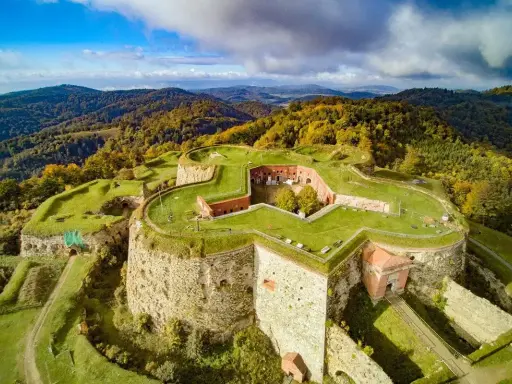 Twierdza w kształcie gwiazdy na wzgórzu, otoczona jesiennymi lasami. To malowniczy wschód Polski, gdzie historia spotyka się z naturą.