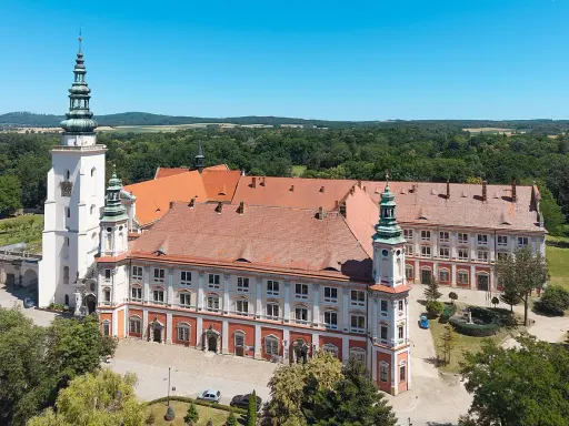 Imponujący Henryków zamek z wieżami i czerwonymi dachami, otoczony zielenią.