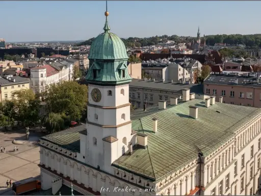 Widok na rynek na Kazimierzu w Krakowie z wieżą ratuszową i zielonymi dachami.