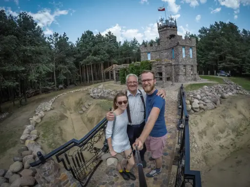 Rodzina pozuje do zdjęcia na tle kamiennego zamku, jednego z romantycznych miejsc na Podlasiu.