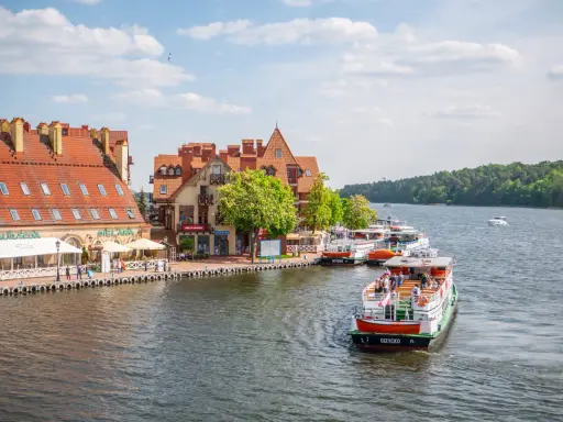Port w Giżycku, gdzie cumują statki wycieczkowe, to jedna z głównych atrakcji miasta. W tle malownicze kamieniczki i zielone lasy.