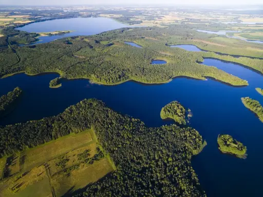 Malownicze jeziora na Mazurach otoczone gęstymi lasami, z widokiem na pola i dalsze akweny.