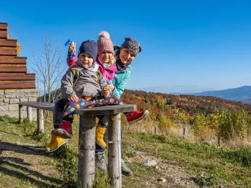 Rodzina na ławce z widokiem na jesienne góry. Góra Modyń w tle.
