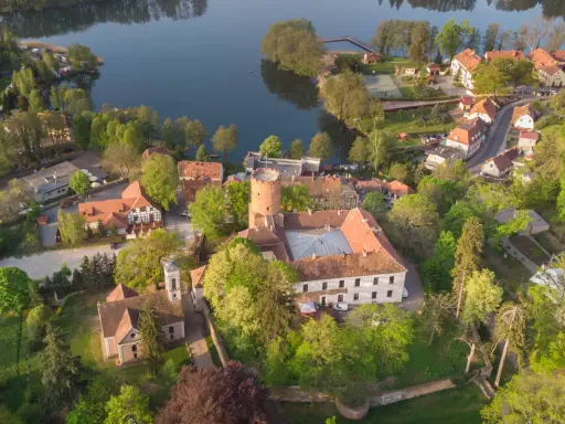 Malowniczy zamek i jezioro, idealne na wycieczki jednodniowe lubuskie. Wiosenna zieleń otacza zabytkowe budowle i spokojną taflę wody.