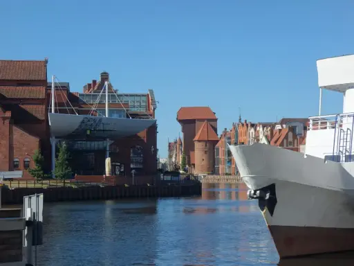 Gdańsk Starówka atrakcje: biały statek na pierwszym planie, w tle zabytkowe kamienice i Żuraw.