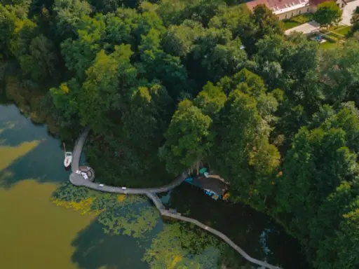Idealne miejsce, gdzie nad jezioro w Polsce. Drewniana kładka prowadzi do łodzi i żaglówki, otoczone bujną zielenią.