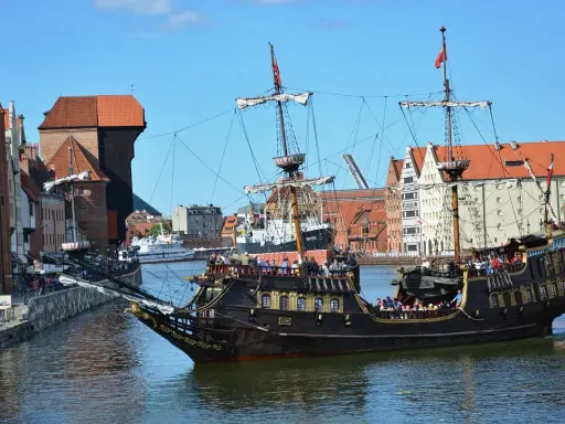 Gdański galeon "Lew" z pasażerami na pokładzie, na tle zabytkowej architektury miasta. To jeden z 7 ciekawych faktów o Polsce, które można odkryć w tym mieście.