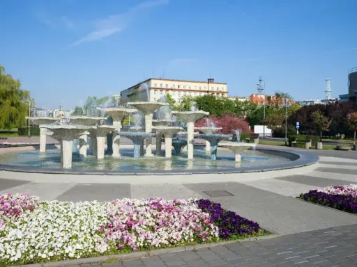 Fontanna w Gdyni stare miasto, otoczona kolorowymi kwiatami i zielenią, stanowi serce miejskiego placu.