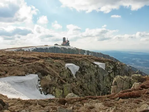 Szklarska Poręba jakie góry? Widok na Karkonosze z budynkiem na szczycie, skaliste zbocza i resztki śniegu.