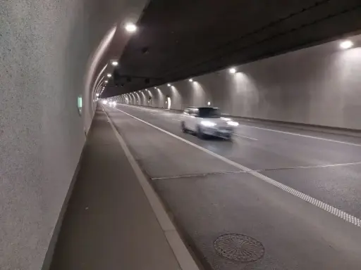 Biały samochód mknie przez oświetlony tunel w Zakopanem.