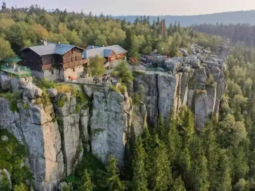 Schronisko na skalnej półce w Sudetach, Polska. Ludzie odpoczywają na tarasach z widokiem na las.