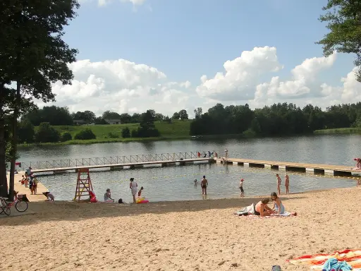 Słoneczne plaże na Mazurach. Ludzie odpoczywają na piasku i w wodzie, ciesząc się letnim dniem.