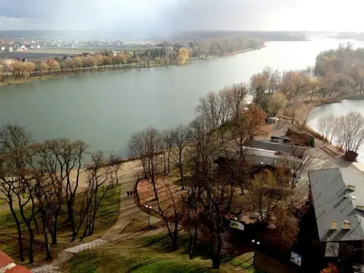 Malownicze jeziora w Kujawsko-Pomorskim, z drzewami w jesiennych barwach i miastem w tle.