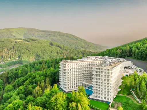 Nowoczesny hotel wtopiony w zieleń gór, przypominający kształtem górę czaszki.
