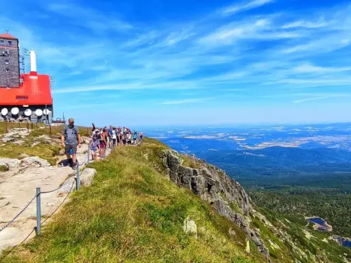 Grupa turystów wędruje ścieżką na Łabski Szczyt, podziwiając rozległą panoramę gór i dolin.