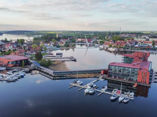 Mazury słyną z malowniczych jezior i portów pełnych jachtów. Widok na miasteczko z nowoczesnymi budynkami i wodnymi atrakcjami.