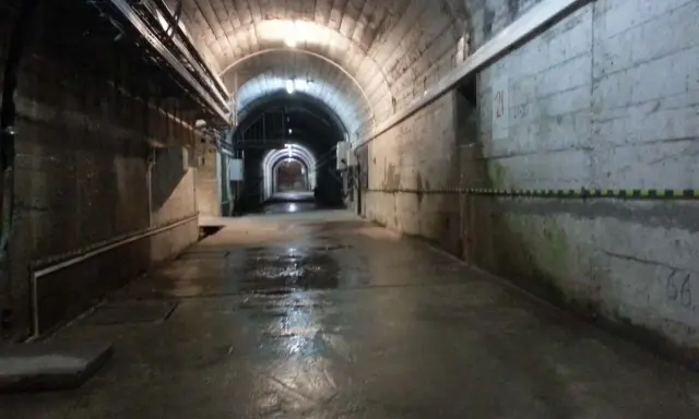 Wnętrze tunelu podczas zwiedzania elektrowni Solina. Mokra posadzka odbija światło lamp.