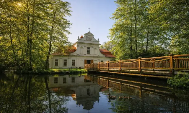 Urokliwy dworek otoczony zielenią, z drewnianym mostkiem i kaczą rodziną na stawie. Idealne miejsce na spędzenie **roztocze w jeden dzień**.