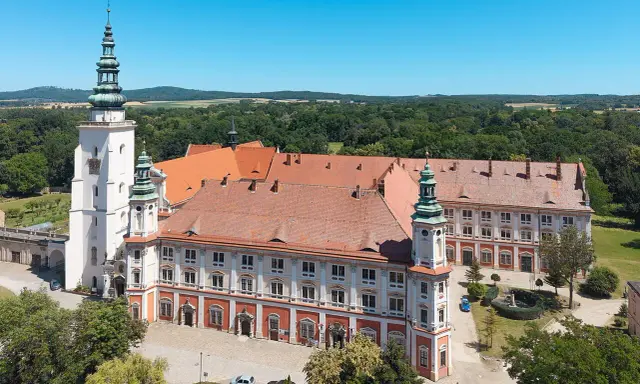 Imponujący Henryków zamek z wieżami i czerwonymi dachami, otoczony zielenią.