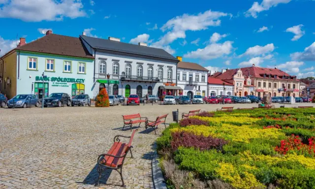 Kolorowy rynek z kwitnącymi rabatami i ławkami, idealne miejsce na wyjazd na weekend.