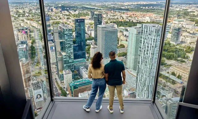 Para zwiedzająca Varso Tower taras widokowy, podziwia panoramę Warszawy.