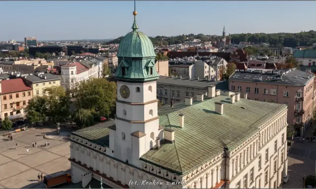 Widok na rynek na Kazimierzu w Krakowie z wieżą ratuszową i zielonymi dachami.
