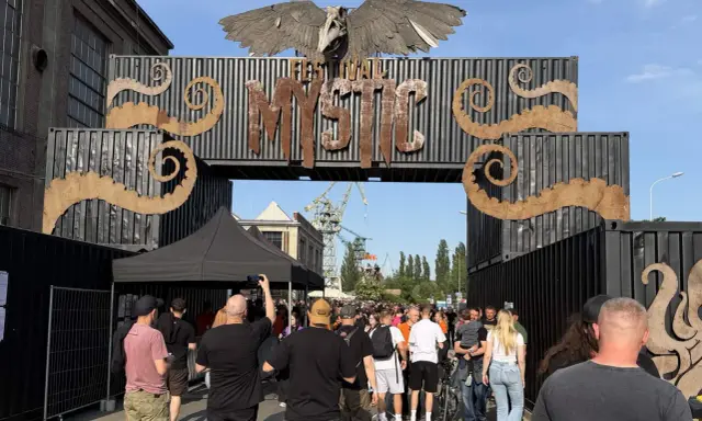 Tłum ludzi wchodzi przez bramę festiwalową "Mystic". To jedno z wielu wydarzeń kulturalnych, takich jak festiwale filmowe w Polsce.