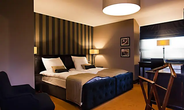 Przytulny pokój hotelowy z dużym łóżkiem, idealny na romantyczny wypad. Co można robić w Lublinie z dziewczyną? Tu na pewno odpoczniecie.