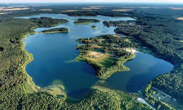 Malownicze jezioro Niesulice otoczone lasami, z wyspami i zabudowaniami na brzegu. Idealne miejsce na wypoczynek.