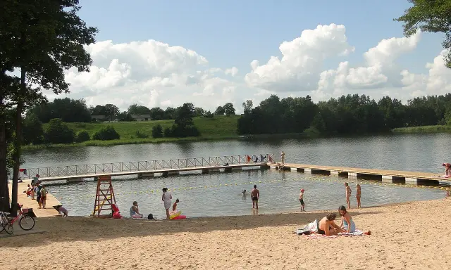 Słoneczne plaże na Mazurach. Ludzie odpoczywają na piasku i w wodzie, ciesząc się letnim dniem.