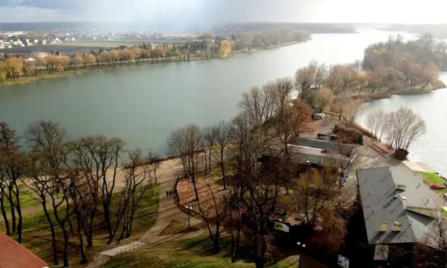 Malownicze jeziora w Kujawsko-Pomorskim, z drzewami w jesiennych barwach i miastem w tle.