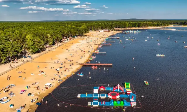 Słoneczny dzień na zalewach świętokrzyskich. Tłumy plażowiczów, wodne atrakcje i mnóstwo łódek na tafli wody.