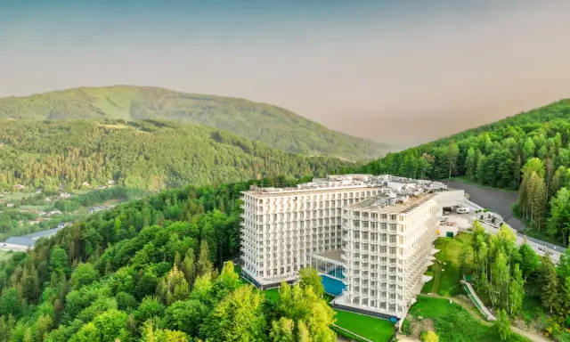 Nowoczesny hotel wtopiony w zieleń gór, przypominający kształtem górę czaszki.