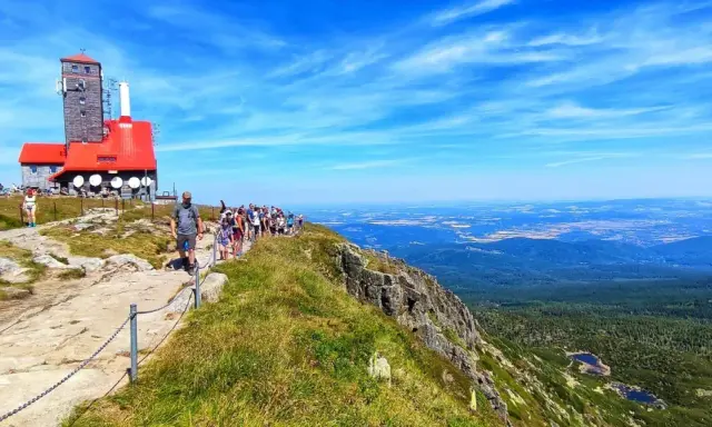 Grupa turystów wędruje ścieżką na Łabski Szczyt, podziwiając rozległą panoramę gór i dolin.