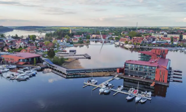 Mazury słyną z malowniczych jezior i portów pełnych jachtów. Widok na miasteczko z nowoczesnymi budynkami i wodnymi atrakcjami.