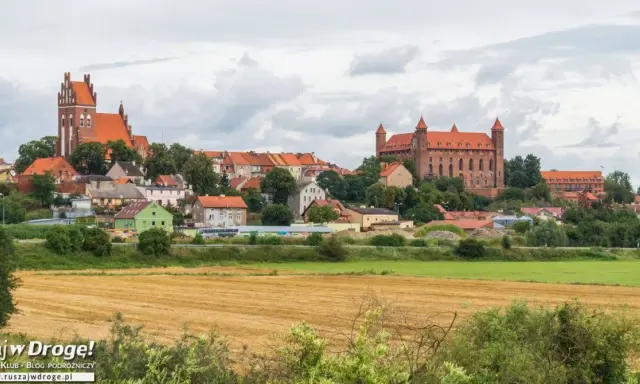 Widok na miasteczko z ceglanymi zamkami i kościołami, otoczone zielenią. W oddali pola uprawne. Wspaniałe **atrakcje** czekają na odkrycie!