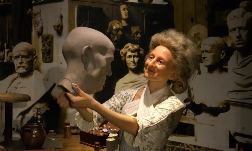 W muzeum figur woskowych artystka w historycznym stroju pracuje nad popiersiem.