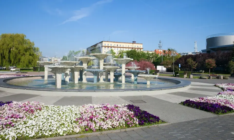 Fontanna w Gdyni stare miasto, otoczona kolorowymi kwiatami i zielenią, stanowi serce miejskiego placu.