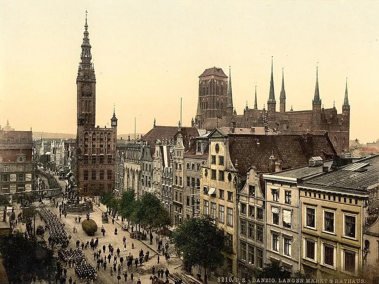 Dawny rynek gdański z Ratuszem i Bazyliką Mariacką w tle. Tłumy ludzi i defilada wojskowa na ulicy.