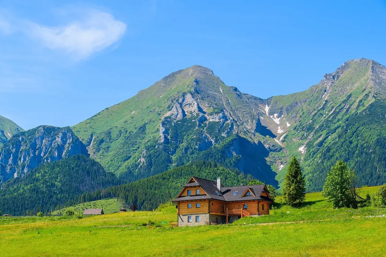 Drewniany domek w sercu zielonych gór. Idealne miejsce na wakacje w górach, z majestatycznymi szczytami w tle.