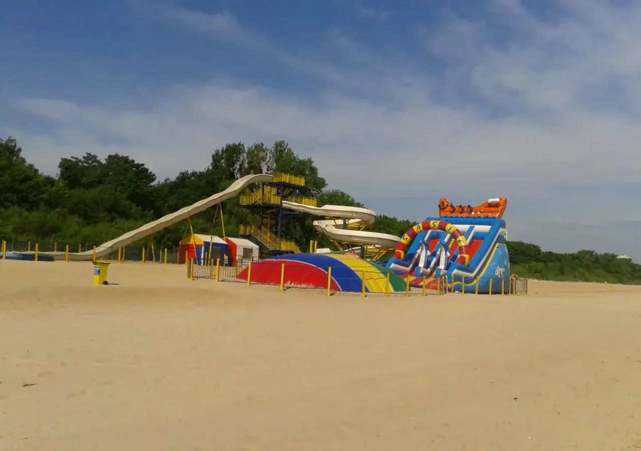 Kolorowe zjeżdżalnie i dmuchane atrakcje na plaży, idealne dla rodzin szukających rozrywki w miejscowościach blisko Trójmiasta.