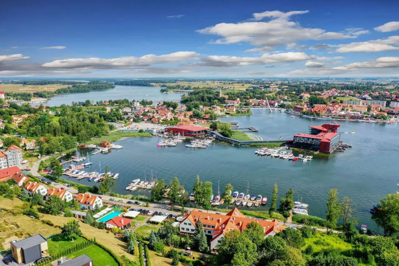 Malownicze mazury miasta z widokiem na jezioro i liczne łodzie.