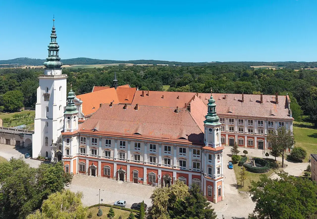 Imponujący Henryków zamek z wieżami i czerwonymi dachami, otoczony zielenią.