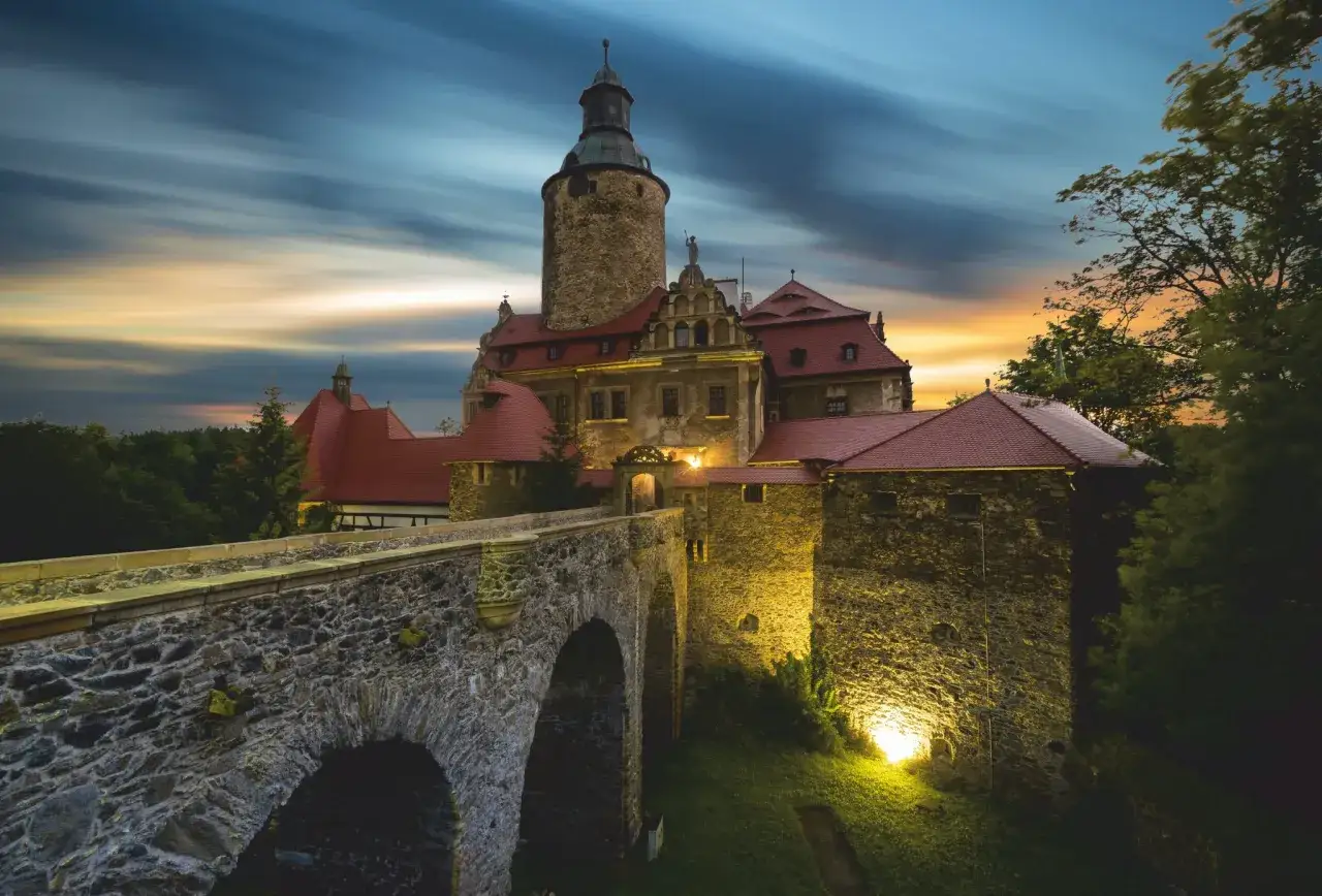 Kamienny most prowadzi do oświetlonego zamku o zachodzie słońca. Idealne miejsce na wycieczka jednodniowa.