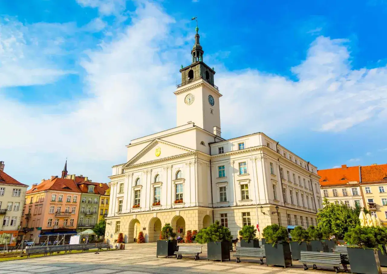 Ratusz w Kaliszu, najstarszym mieście w Polsce, na tle błękitnego nieba z chmurami.