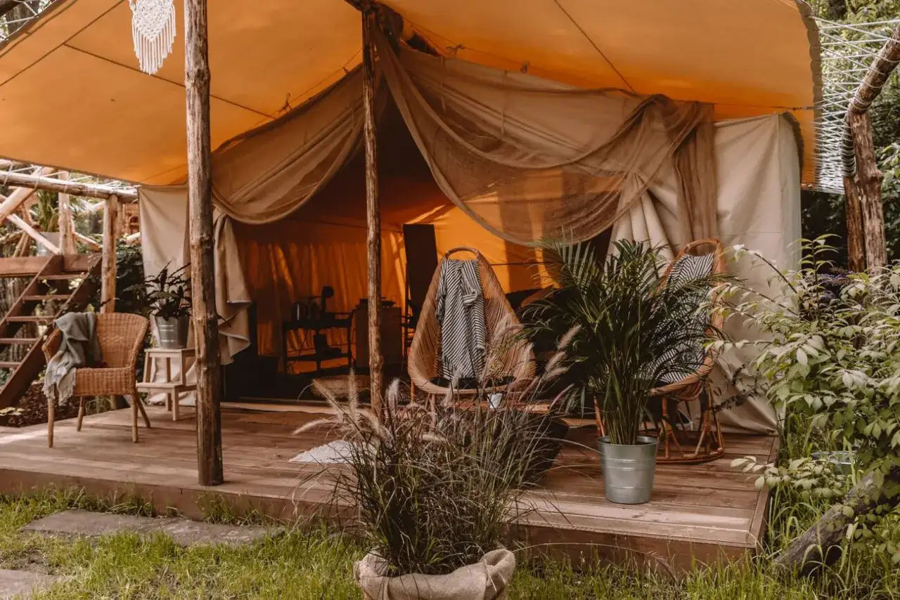 Wygodny namiot kimura glamping z wiklinowym fotelem i roślinami. Idealne miejsce na relaks na łonie natury.
