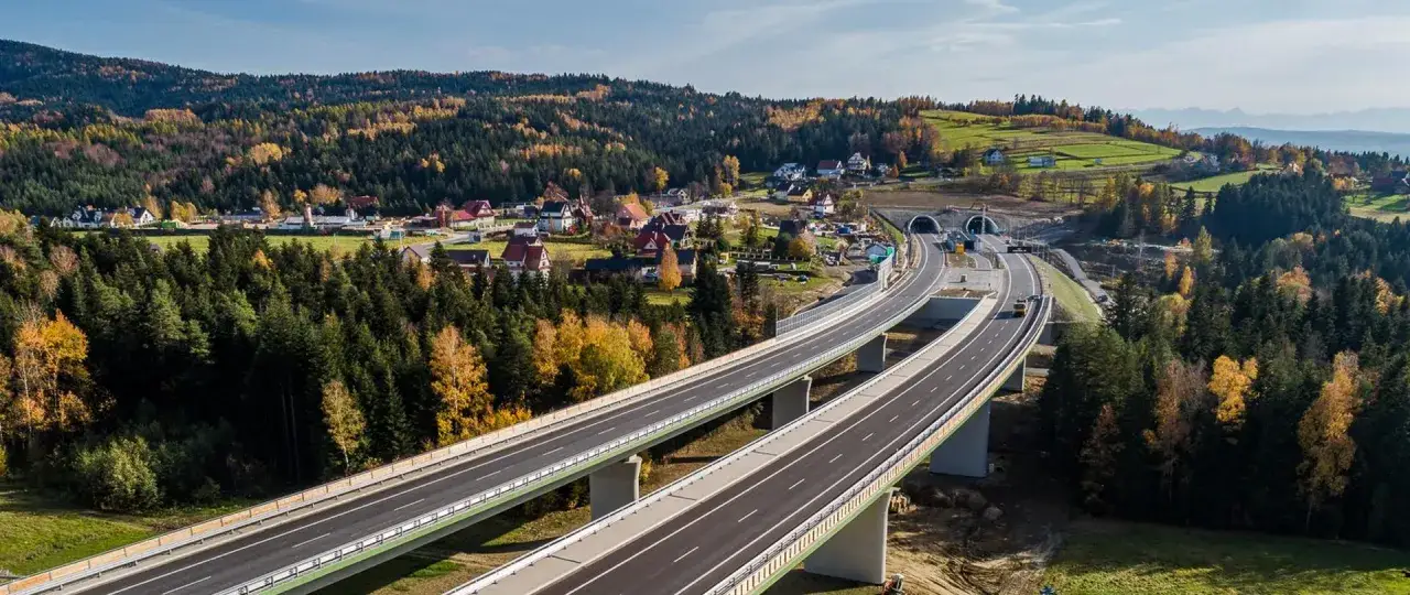 Nowa droga ekspresowa z wiaduktami i tunelem w Zakopanem, otoczona jesiennym lasem i górami.